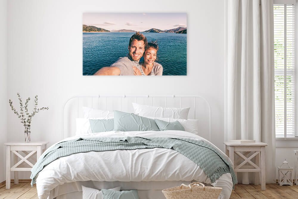 Rahmenloses Wandbild von einem Pärchen, dass ein Selfie am Meer macht hängt im Schlafzimmer über dem Bett. 