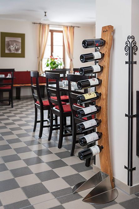WineSir-Weinhalter in Eiche natur für neun Flaschen mit einem Sockel aus Stahl steht am Gang eines Restaurants. 